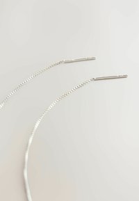 Sølvkædeøreringe med tynde, forlængede stænger i enderne; har et strømlinet, minimalistisk design og en glat metallisk tekstur.
