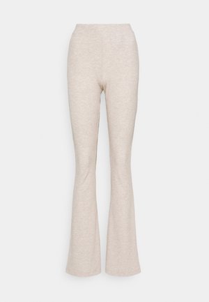 Beige ribbade stickade byxor med hög midja och lätt utställda ben mot en plain vit bakgrund.