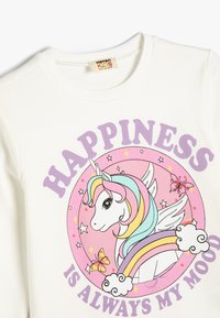 Sudadera de algodón blanca con un gráfico de unicornio. El texto dice "LA FELICIDAD SIEMPRE ES MI ESTADO DE ÁNIMO" en púrpura, sobre un fondo rosa y un colorido arcoíris.