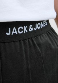 Černé šortky s elastickým pasem, na kterém je bílé logo "JACK & JONES". Měkká, strukturovaná tkanina s volným střihem.