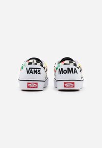 Paire de baskets Vans blanches avec un motif damier coloré, "VANS" au talon gauche, "MoMA" au talon droit, et le logo rouge Vans "Off The Wall".