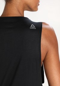 Black sleeveless athletic top made of smooth fabric, featuring a Reebok logo in gray on the upper back area.