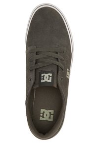 DC Schuhe, grüne Wildleder-Oberfläche, Schnürdesign, gepolsterte Zunge, weiße Gummisohle mit schwarzen Akzenten und Logo auf der Innensohle. Nahtdetails sichtbar.