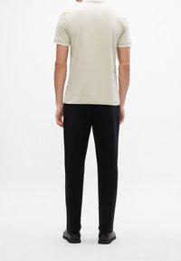 Polo shirt gris clair à manches courtes, assorti à un pantalon noir et des chaussures noires décontractées. Design simple avec une texture propre et lisse.