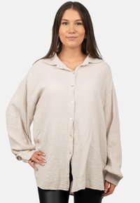 Lichtbeige knoopshirt van textuurstof, met een kraag, lange mouwen en een oversized pasvorm met een licht gebogen zoom.