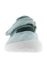 Zapato de lona azul claro con una correa, suela de goma blanca, puntera redondeada y lados abiertos para mayor transpirabilidad. Presenta un acento de hardware en tono dorado.