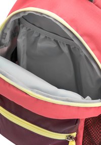 Interno dello zaino con fodera grigia morbida, esterno rosso e bordeaux, dettagli gialli sulla cerniera e una tasca in rete. Design compatto e funzionale.