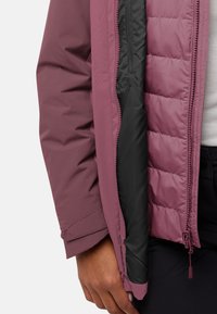 Bordeauxjack met een rits in zwart, gebreide textuur en elastische manchetten. Gevoerde ritsdetails en een gladde buitenafwerking.