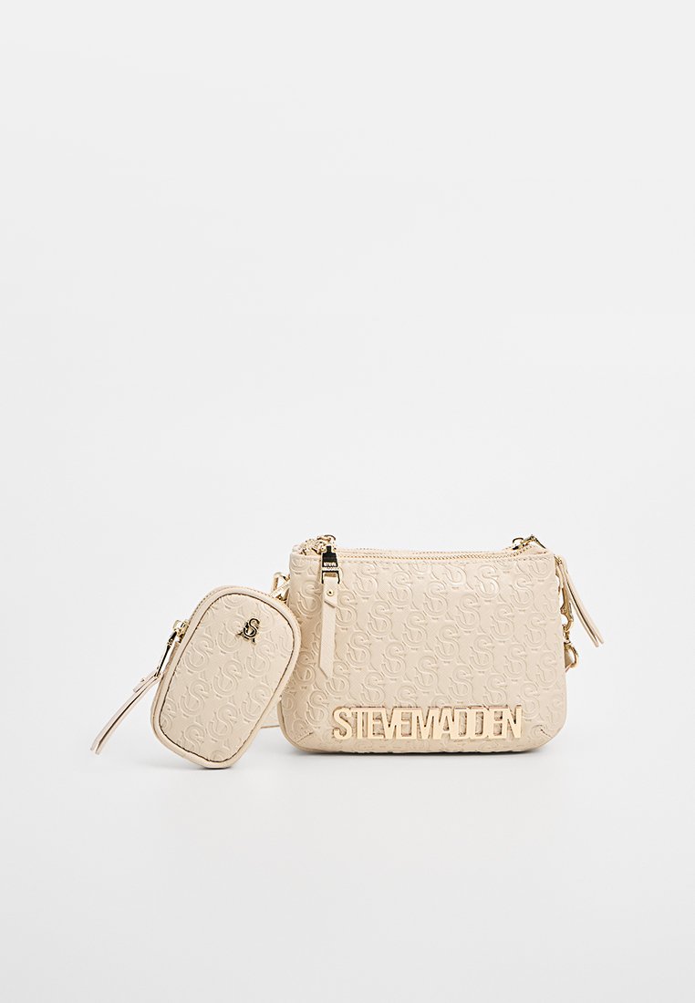 Sac bandoulière beige avec un motif de logo en relief, des éléments en métal doré et une petite pochette amovible, dotée de fermetures éclair et d'une surface texturée.