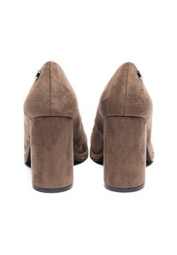Scarpe con tacco alto in suede marrone, con tacco grosso e punta affusolata. Nota accentatura in metallo lucido sulla parte posteriore. Superficie testurizzata.