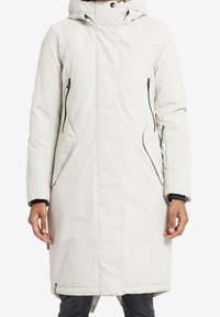 Pitkä valkoinen untuvapuku hupulla, jossa on vetoketjulliset sivutaskut, kontrastoivat mustat vetoketjut ja sileä, teksturoitu pinta.