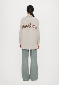 Striped shirt in beige and white with embroidered "MAX&CO" on the back; paired with wide-leg light blue jeans.