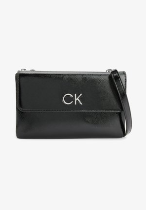 Černá kabelka přes rameno z lesklého syntetického materiálu se stříbrným logem CK. Má překládanou klopu a odnímatelný popruh. Obdélníkový tvar.