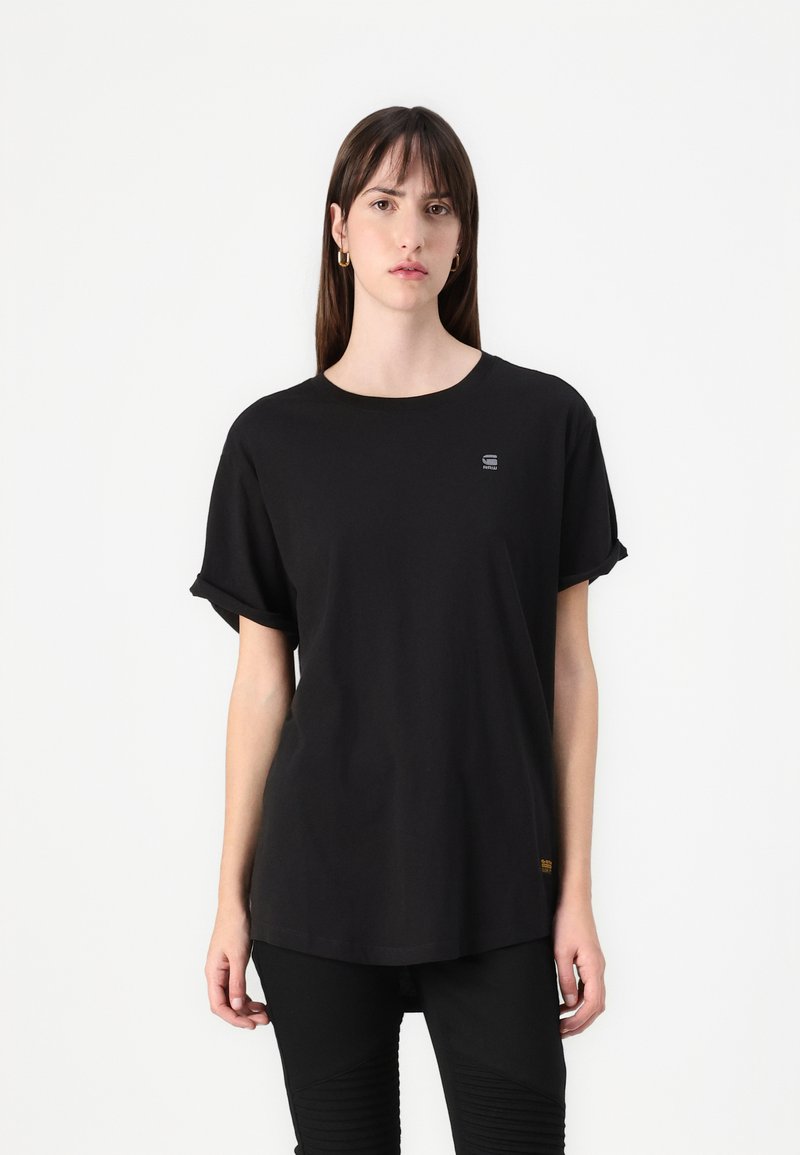 Black oversized t-shirt made from cotton. Short rolled sleeves, round neckline, small logo detail on chest, falls to hips. Classic cut.