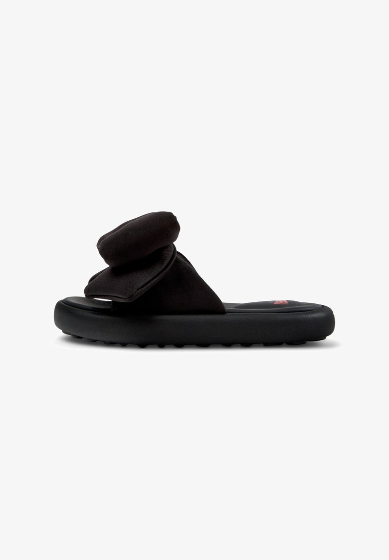 Chancla negra con parte superior suave y acolchada y suela de goma contorneada con agarre texturizado. Diseño minimalista con lados abiertos.