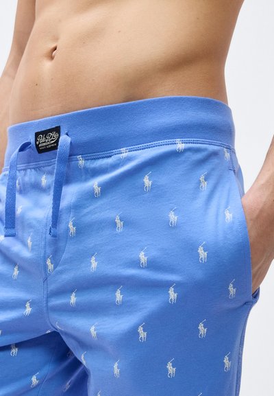 Γυμνό πάνω μέρος του σώματος που φοράει ανοιχτό μπλε σορτσάκια με κορδόνι και μικρά λευκά λογότυπα παίκτη πόλο, και μαύρη ετικέτα μάρκας στη μέση.