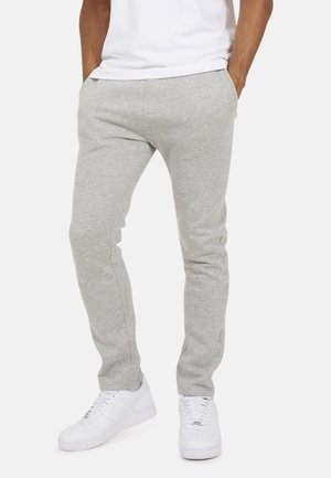 Szare dresy wykonane z miękkiego materiału, charakteryzujące się slim fit, elastycznym pasem i bocznymi kieszeniami, w połączeniu z białymi trampkami.