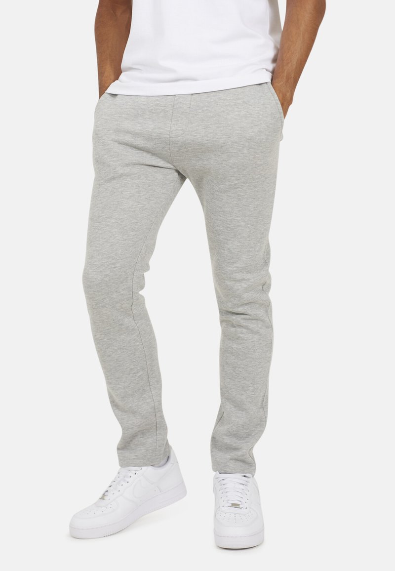 Szare dresy wykonane z miękkiego materiału, charakteryzujące się slim fit, elastycznym pasem i bocznymi kieszeniami, w połączeniu z białymi trampkami.