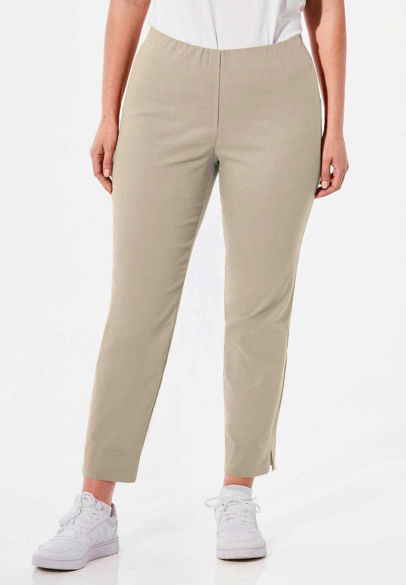 Beige, rekbare broek met een elastische tailleband en een enkel-kort ontwerp. De stof heeft een gladde textuur en heeft zijsplitten bij de boorden.