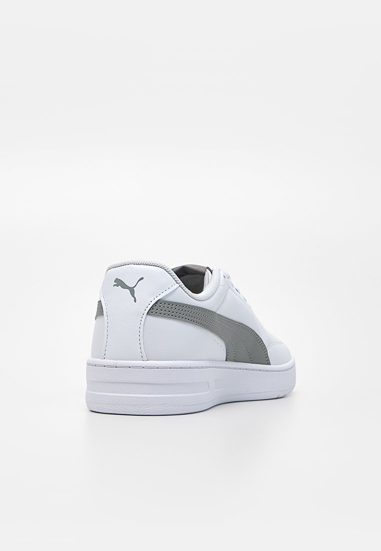 Zapatillas deportivas de cuero blanco con acentos grises, puntera redonda, suela acolchada y logo prominente en el talón. Textura suave con un diseño elegante.