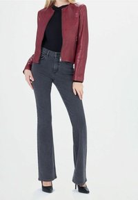 Punainen nahkatakki pyöreällä kaula-aukolla; yhdistetty korkeavyötäröisiin harmaisiin levenevät farkkuihin ja mustiin korkeisiin korkoihin. Suuri tekstuuri, napakka muotoilu.