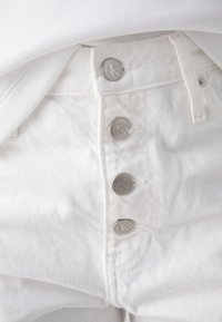 Λευκά τζιν παντελόνια από βαμβάκι με ψηλή μέση, διαθέτουν πέντε κεντρικά μεταλλικά κουμπιά με ανάγλυφο το "CK" και ήπια υφή.