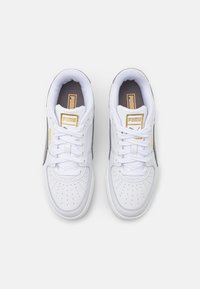 Vita sneakers med perforerad tå och tunga, snörning, grå detaljer och en gullloggtagg. Gummisula och vadderad krage för komfort.