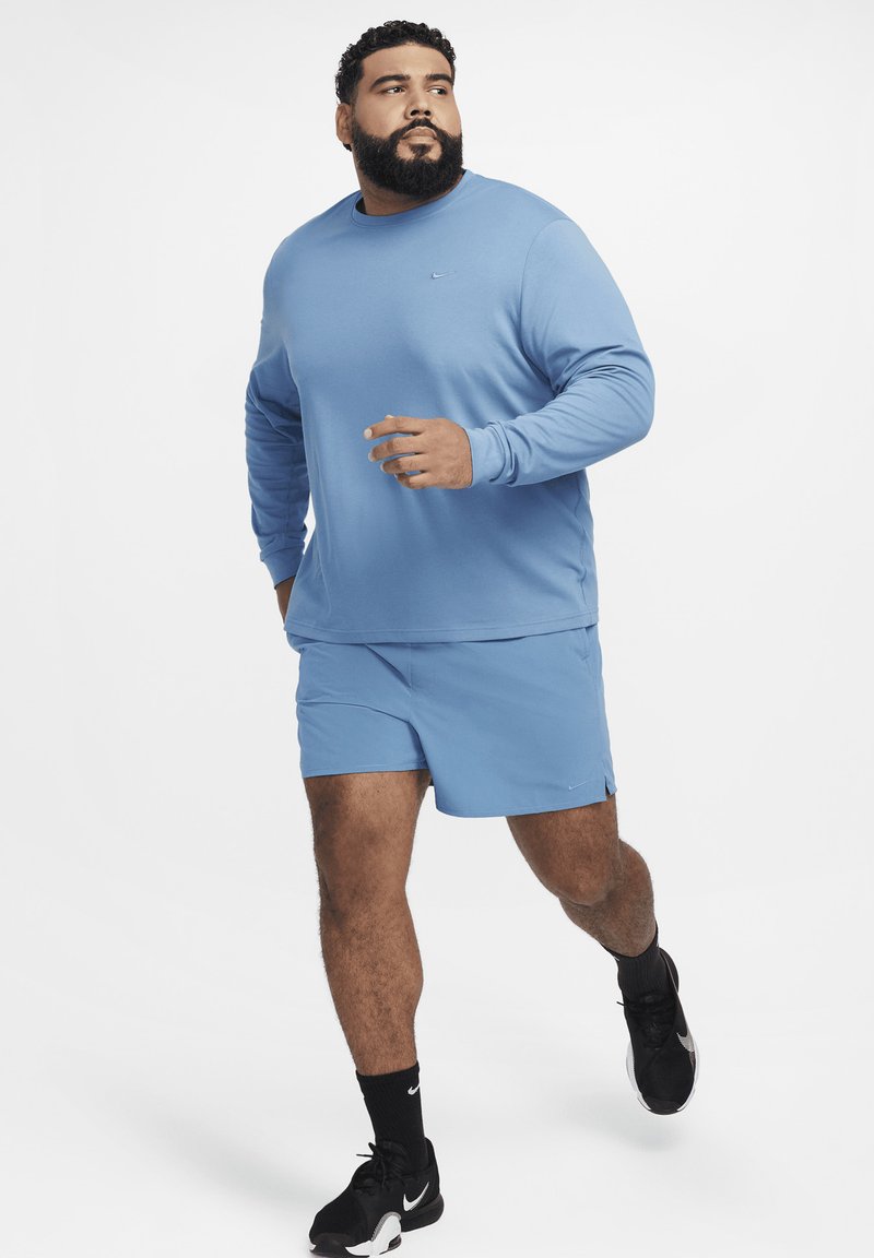 Jasnoniebieska koszula z długim rękawem i pasujące szorty, wykonane z miękkiego materiału, w zestawie z czarnymi butami sportowymi, zaprojektowane do biegania.