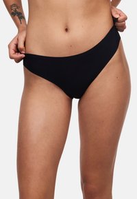 Sort bikiniunderdel med sømløst design, lav talje og glat tekstur. Minimalistisk stil uden synligt hardware eller mønstre.