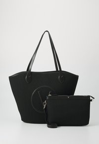 Borsa tote nera con tessuto strutturato, manici in pelle liscia e un logo circolare prominente. Include una pochette coordinata con cerniera.