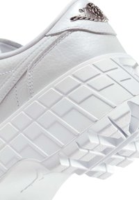 Baltas ādas sneakeris ar tekstūru vidējā zole, rakstainā ārējā zole un metalizēta akcenta elements uz papēža. Minimālistisks dizains un gluda apdare.