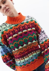 Sweter dzianinowy z wysokim pomarańczowym ściągaczem, z wielokolorowymi geometrycznymi wzorami w kolorach zielonym, różowym, niebieskim i kremowym. Teksturowana wełniana tkanina.