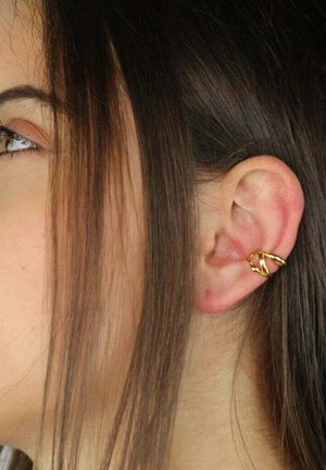 Orecchino a polsino intrecciato in oro con design a strati, caratterizzato da una forma aperta con finitura testurizzata, indossato sull'orecchio di una modella.