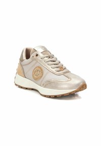 Zapatilla metálica beige con panel lateral texturizado, punta redonda y diseño con cordones. Cuenta con un logo y suela de goma para mayor tracción.
