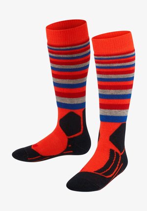 Chaussettes montantes aux genoux avec un schéma de couleurs rouge vif et marine, ornées de rayures horizontales grises et bleues, et d'un design noir en accent sur le pied.
