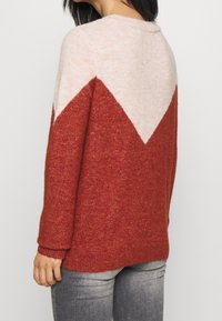 Röd och ljusrosa färgblockerad tröja med V-formad design på baksidan, har en mjuk textur och långa ärmar.