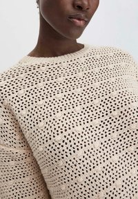 Strickpullover in cremefarbener Farbe, mit einem strukturierten Muster aus durchbrochenen Elementen und Zickzackstreifen. Rundhalsausschnitt mit geripptem Saum.