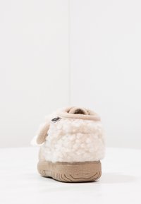 Bottines beige texturées avec un sommet duveteux, des accents lisses couleur tan, une fermeture éclair et une semelle en caoutchouc dotée d'un motif de tread ondulé.