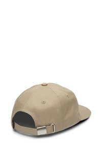 Gorra de béisbol beige con visera curva, hecha de tela texturizada. Presenta un cierre de metal y una correa ajustable en la parte trasera.