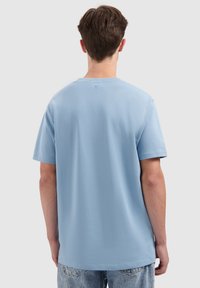 Korte mouwen T-shirt in lichtblauwe katoen met een ronde hals, met een klein accentdetail aan de achterkant van de halslijn. Casual fit.
