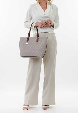 Grå quiltet skuldertaske med brune læderstropper og en cirkulær metaldekoration. Har en rektangulær form og en solid bund med tydelige syninger.