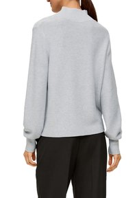 Hellgrauer, langärmeliger Pullover mit hohem Ausschnitt, gerippten Bündchen und Saum; gestrickte Textur mit lockerer Passform und minimalistischem Design.