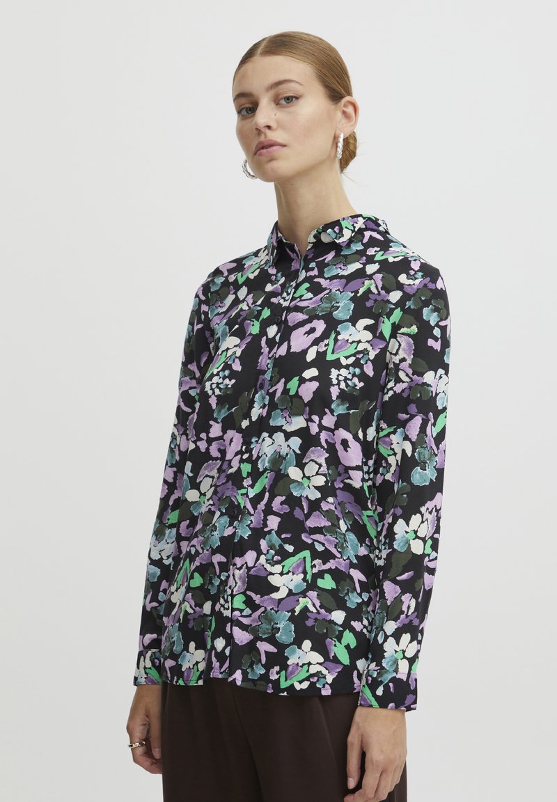 Long-sleeve shirt in black fabric with a colorful floral pattern in purple, green, and white. Features a button-down front and collar.