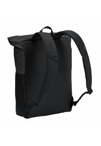 Mochila negra con correas acolchadas, parte superior plegable, bolsillo lateral con cremallera y textura suave. Presenta un logo sutil en el panel trasero.