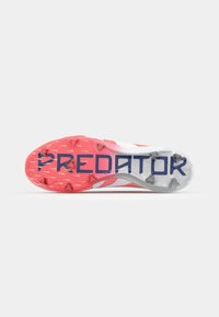 Scarpe da calcio Predator, con una suola rossa e bianca e punte trasparenti, e un marchio blu sul fondo. Texture liscia e design aerodinamico.