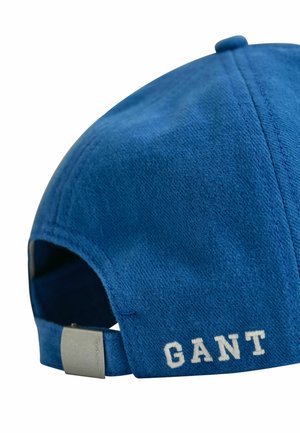 Blauwe stoffen baseballpet met verstelbare band met metalen gesp en witte "GANT" tekst geborduurd op de achterkant.