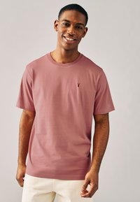 Kurzärmeliges T-Shirt mit Rundhalsausschnitt in staubigem Rosaton, aus Baumwolle gefertigt, mit einem kleinen gestickten Logo auf der linken Brust.