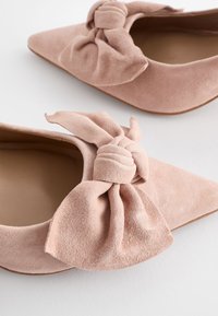 Roosa suède lapikad kingad terava ninaga ja suure, sõlme stiilis kaunistusega ees. Sile sisemus ja peen tekstuur.