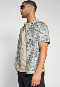 Short-sleeve skjorte i lyseblå med fargerike geometriske og naturinspirerte mønstre, med knappelukking og en avslappet passform.