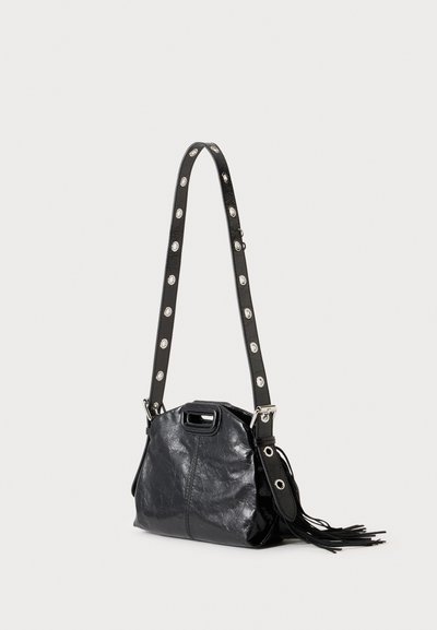 Sac à épaule en cuir noir avec une bandoulière réglable comportant de grands œillets argentés et un détail à franges sur un côté.